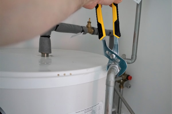 Plumber working on a water heater with tools